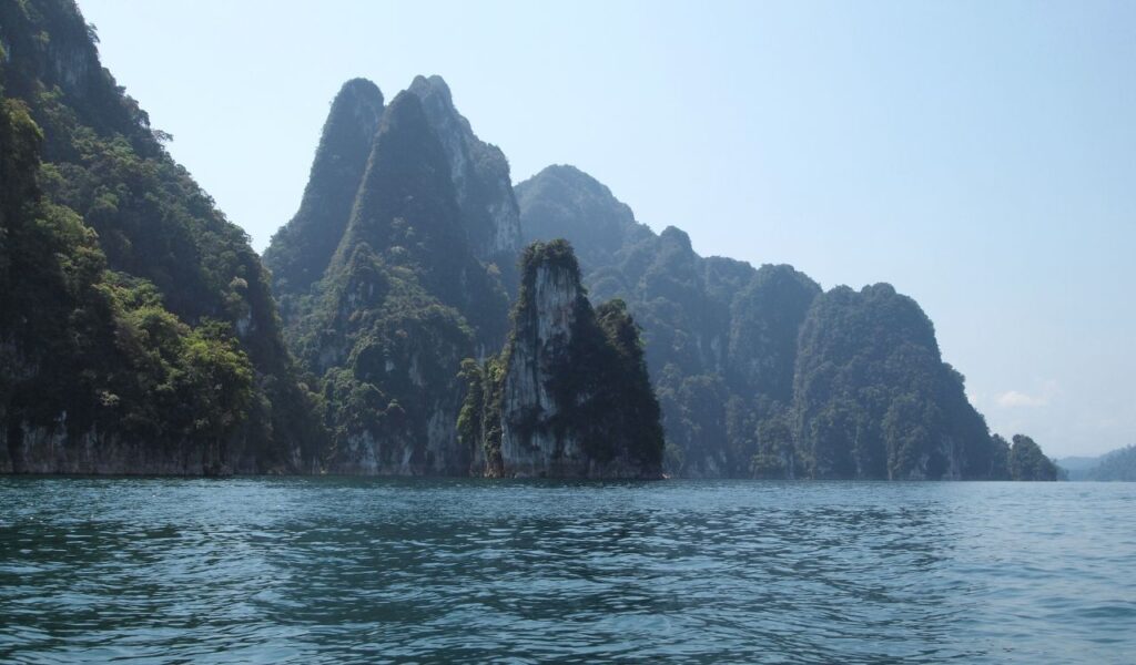 Limestone cliffs rise above blue waters in Thailand’s Cheow Lan Lake.
