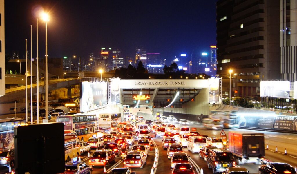 Heavy nighttime traffic entering a tunnel in a brightly lit city, illustrating overnight travel as a budget option