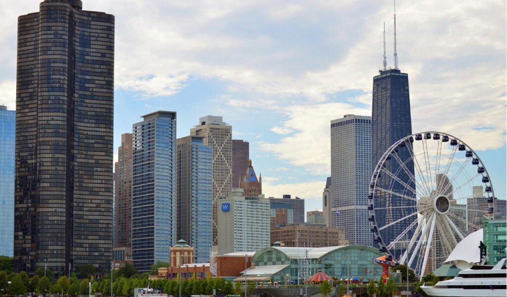 Chicago skyline with tall skyscrapers, Navy Pier Ferris wheel, and boats along the waterfront.