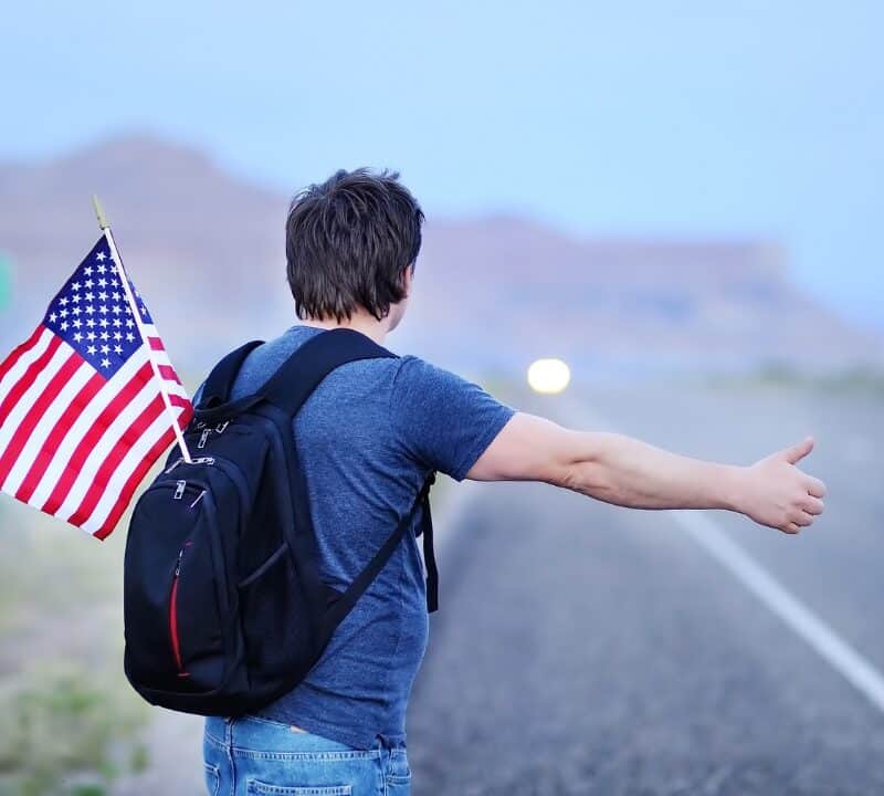 male tourist with american flag in backpack