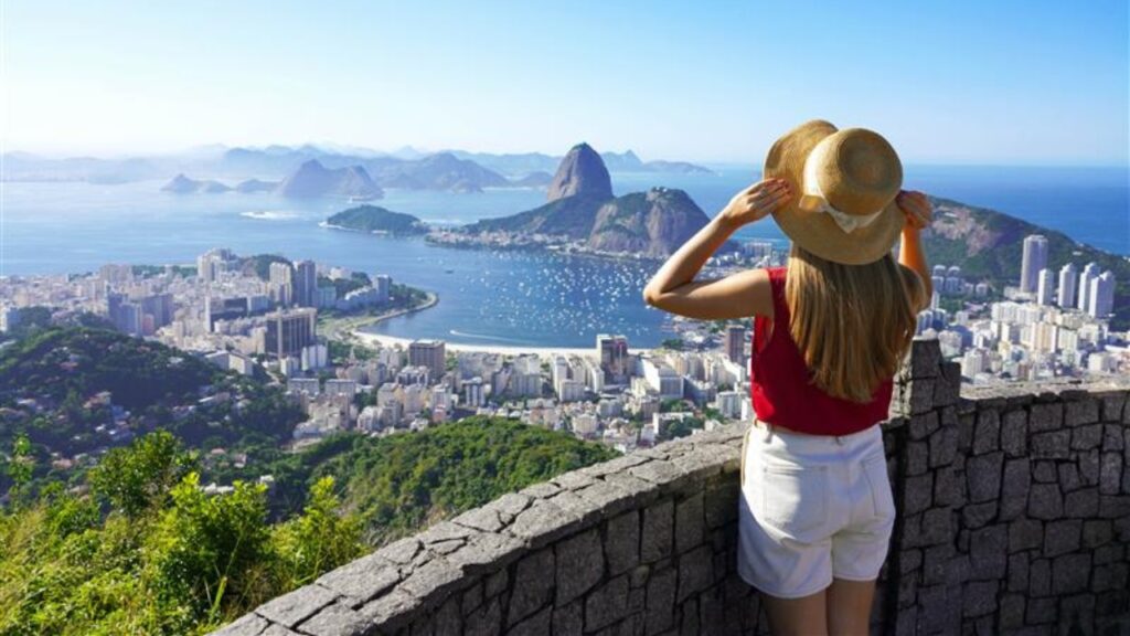 Holidays in Rio de Janeiro. Rear view of tourist woman enjoying sight of famous Guanabara Bay with Sugarloaf Mountain in Rio de Janeiro, UNESCO World Heritage, Brazil