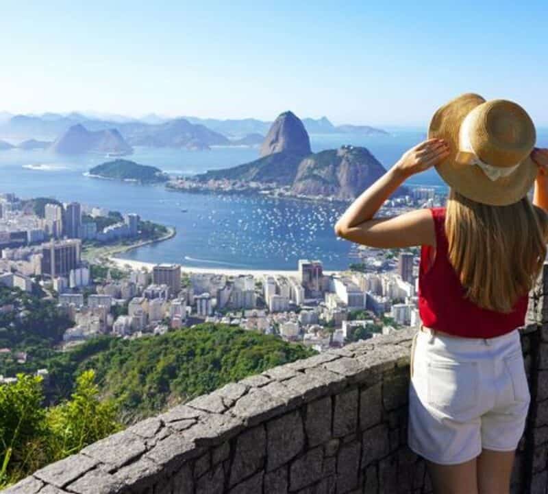 Holidays in Rio de Janeiro. Rear view of tourist woman enjoying sight of famous Guanabara Bay with Sugarloaf Mountain in Rio de Janeiro, UNESCO World Heritage, Brazil