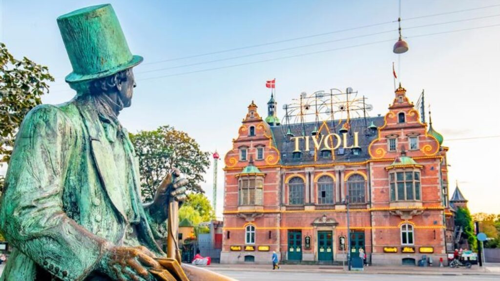 Copenhagen, Denmark - June 19, 2020: Hans Christian Andersen sculpture and entrance to Tivoli Garden park, one of the oldest operating amusement parks in the world