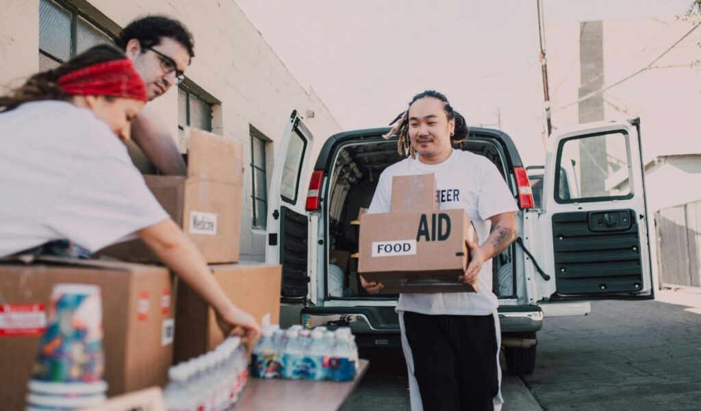 Volunteers unloading aid supplies, including food and medicine, from a van to distribute to the community.