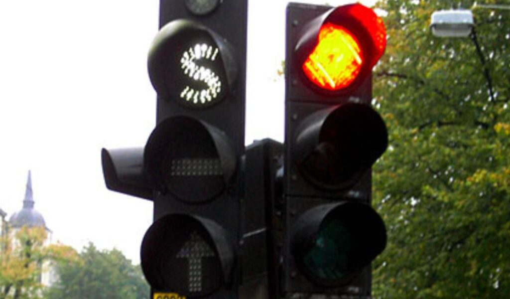 Close-up of a red traffic light and directional signals, emphasizing the importance of obeying all road signals.