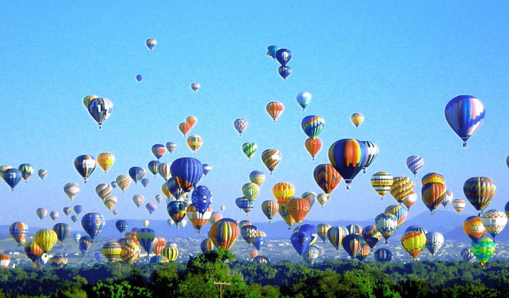 Hundreds of colorful hot air balloons rise into a clear blue sky during the Albuquerque International Balloon Fiesta.