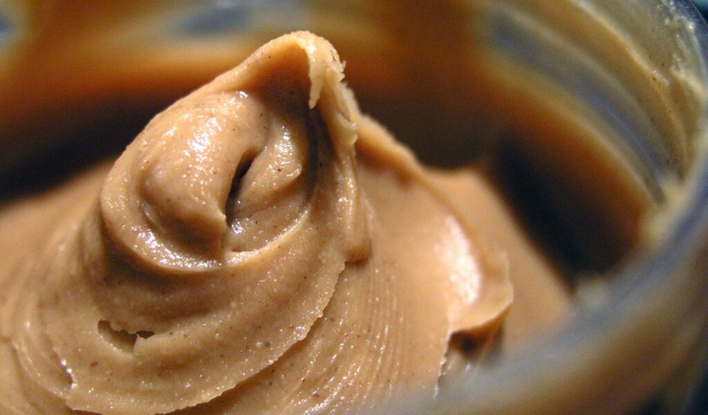 Close-up view of creamy peanut butter swirled inside an open jar, highlighting its smooth, rich texture.