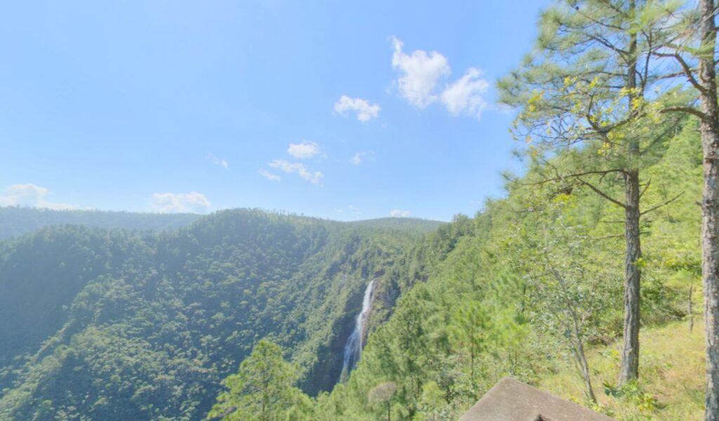 Scenic view of Hidden Valley Falls surrounded by forested mountains in Belize.