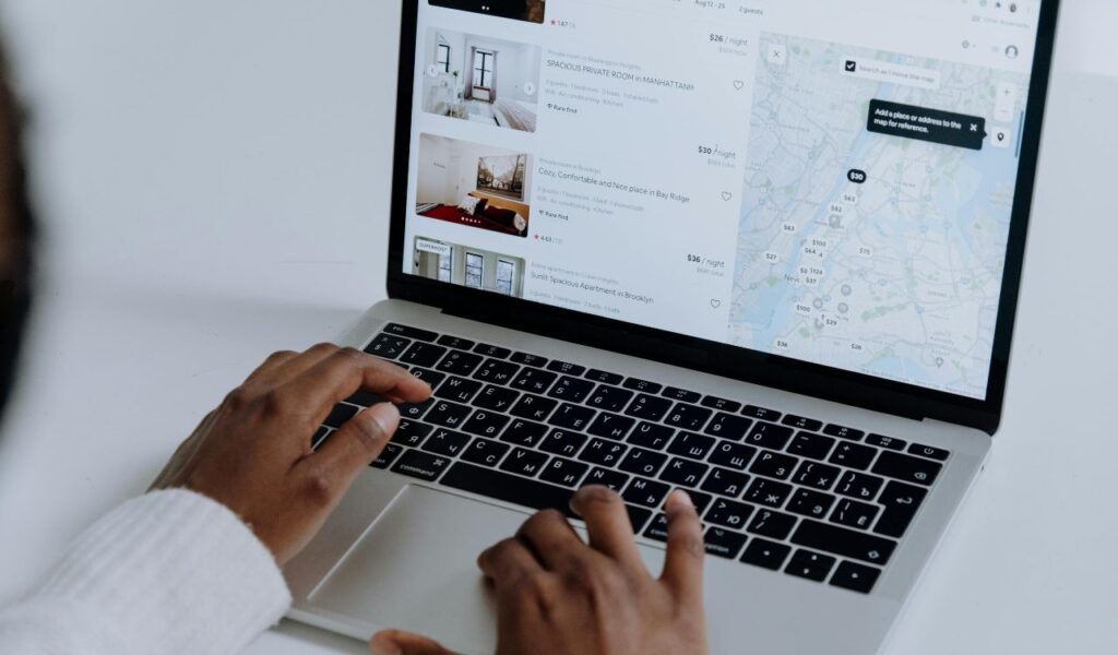 Person browsing accommodation listings and map on laptop while planning and booking a trip in advance.