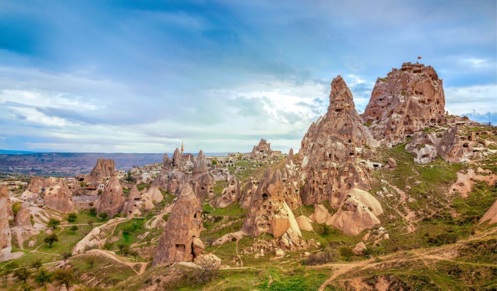Rock formations and ancient cave dwellings in Cappadocia, Turkey, under a dramatic blue sky.