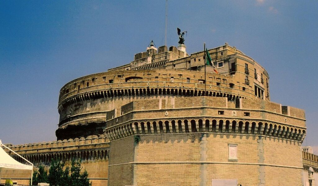 Castel Sant'Angelo in Rome, Italy, with its circular fortress design, Italian flag, and tourists walking nearby.