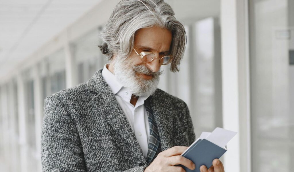 An older man reviewing his travel documents in a passport holder while preparing for his trip, emphasizing the importance of checking travel rules and requirements before departure.
