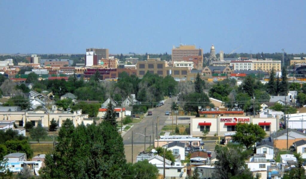 Skyline view of Cheyenne, Wyoming, with houses, trees, and downtown buildings.