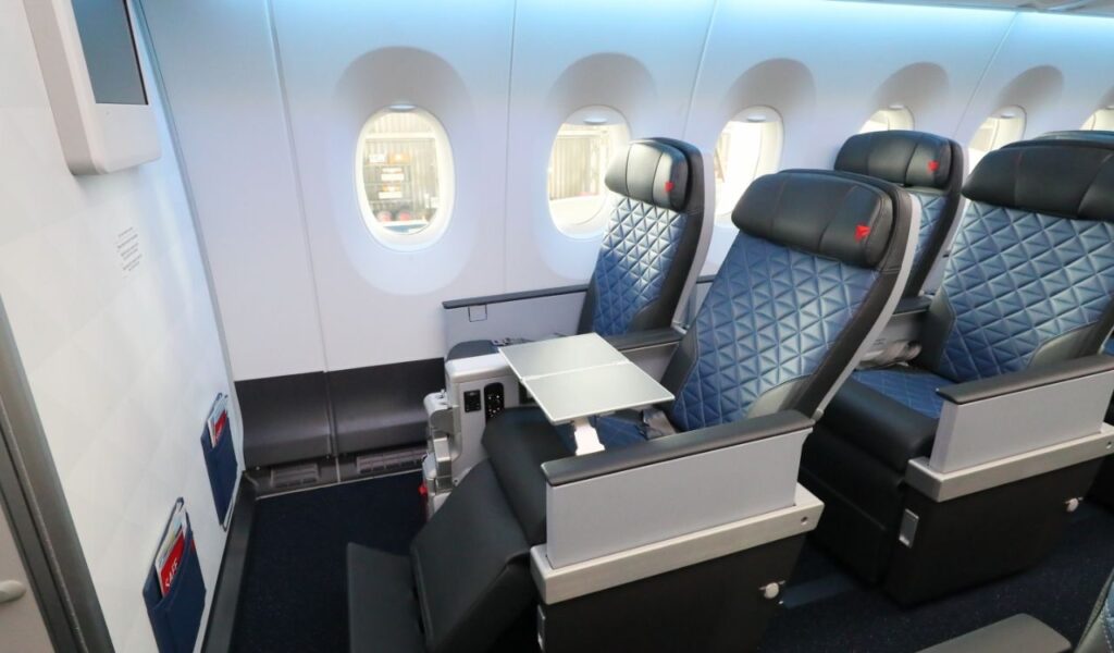 Spacious front-row Delta Premium Select airplane seats with extra legroom and fold-out tray tables near the bulkhead wall.