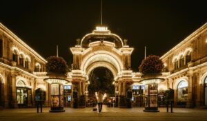 Grand illuminated entrance of Tivoli Gardens in Copenhagen at night, with glowing archways, hanging flower pots, and a person standing in the center holding sparklers.