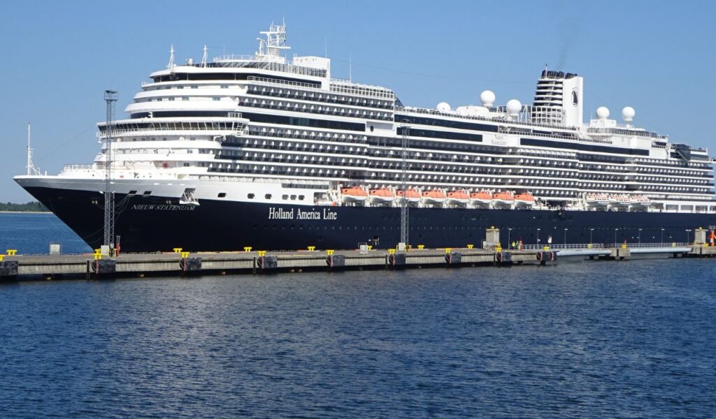 Large Holland America Line cruise ship docked at port, representing cruise bookings and added fees or gratuities onboard.