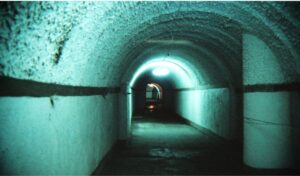 Dimly lit tunnel inside Dixia Cheng underground city in Beijing, China, with curved ceiling and concrete walls illuminated in blue.