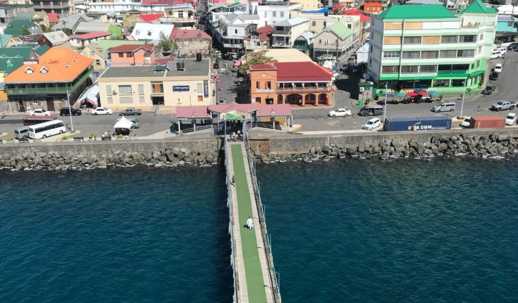 View of Roseau, Dominica’s capital, showing a pier leading into town with colorful buildings and a vibrant waterfront.