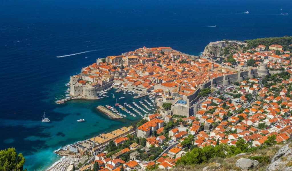 Aerial view of Dubrovnik’s old town with red rooftops and historic stone city walls.