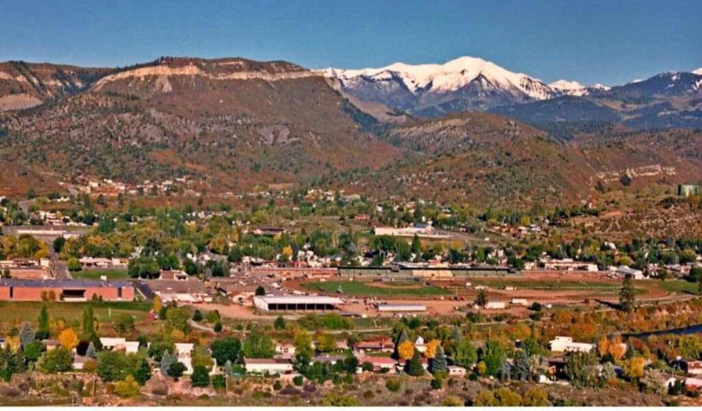 View of Durango, Colorado, with homes, forested hills, and snow-capped mountains in the background.