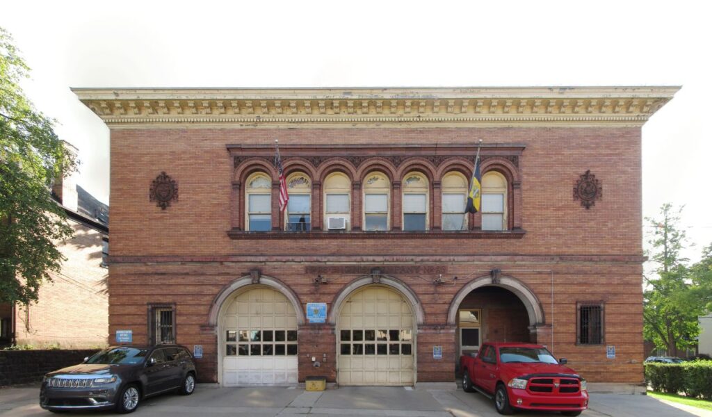 Historic brick firehouse with arched garage doors and upper-floor windows, now converted into Engine Co. No. 28 stay.