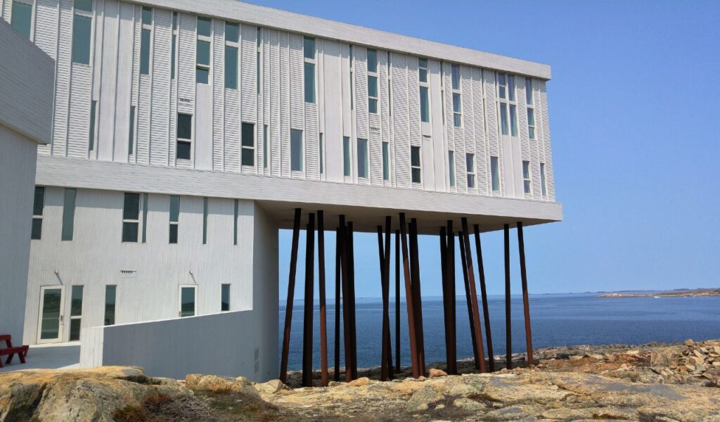 Modern stilted building of Fogo Island Inn overlooking the rocky coastline and blue ocean in Newfoundland, Canada.