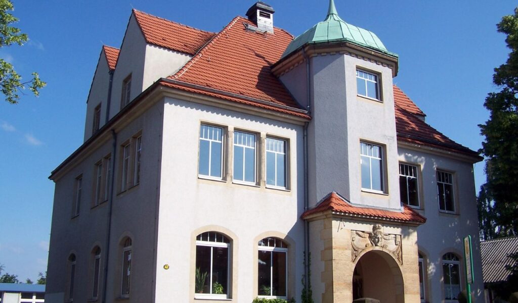 Elegant historical building with a unique turret and red-tiled roof, showcasing classic European architecture.