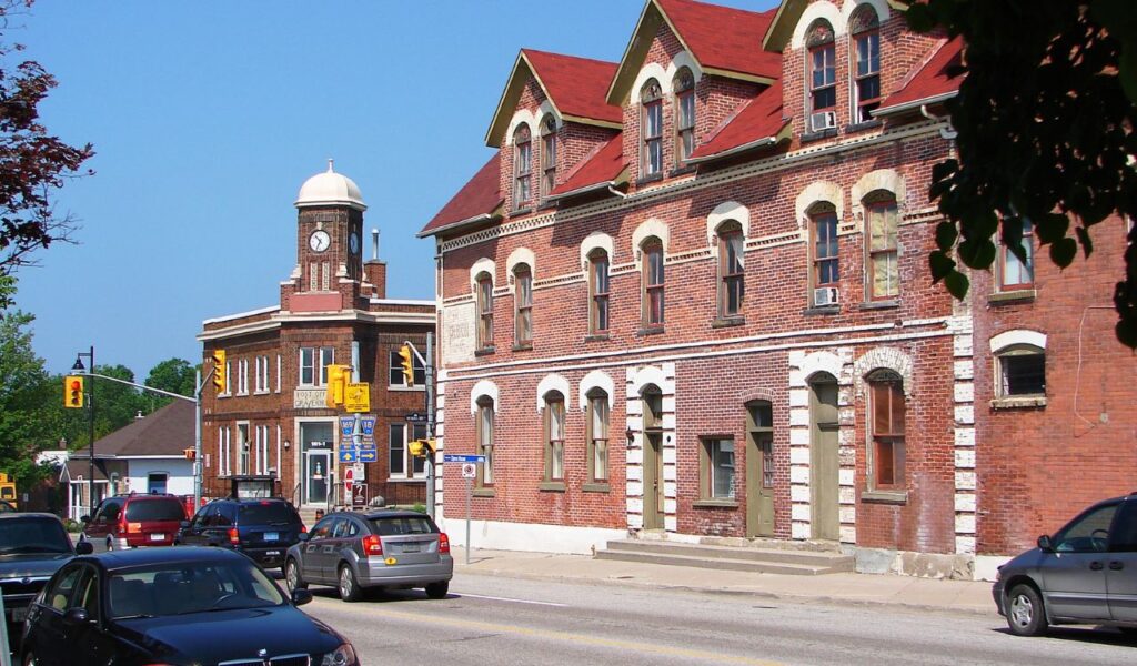 A downtown street in Gravenhurst, Muskoka, featuring historic red-brick buildings, a clock tower, and light traffic on a sunny day.