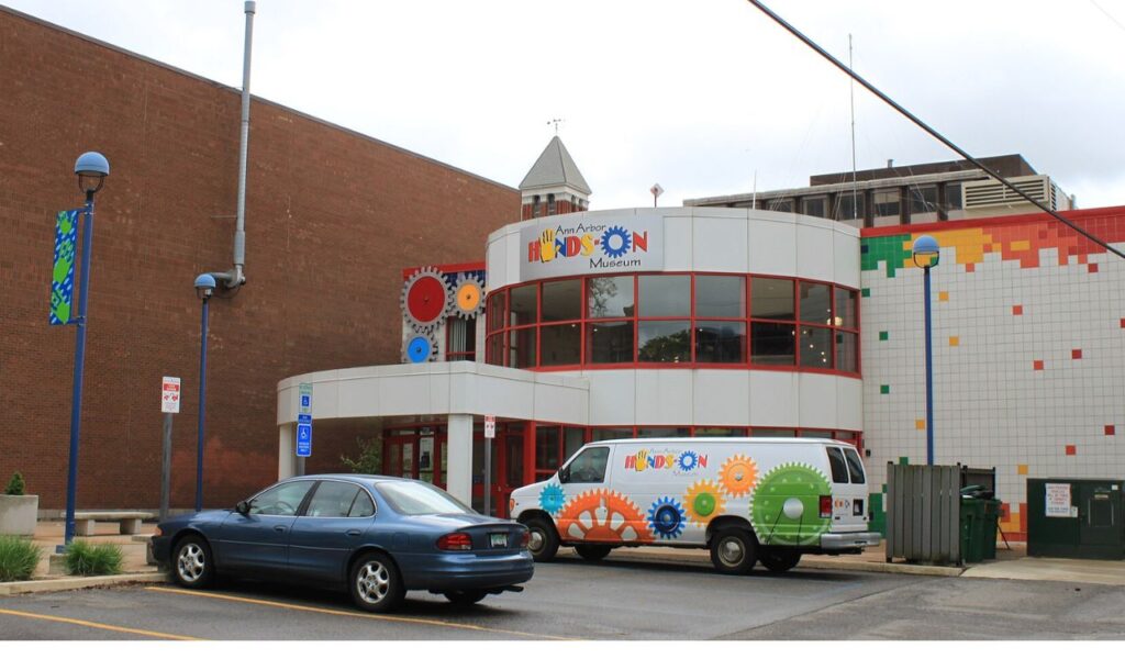Colorful exterior of a children's hands-on museum with bright gear designs and a matching museum van parked outside.