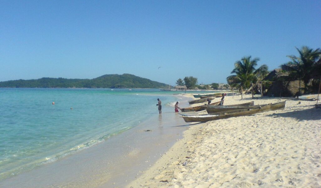 Local fishermen on a white sandy beach with turquoise water in Honduras.