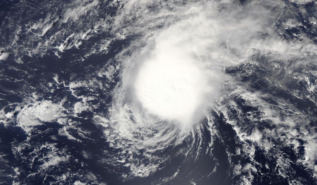 Satellite image of a powerful hurricane forming over the ocean, showing swirling clouds and turbulent weather.