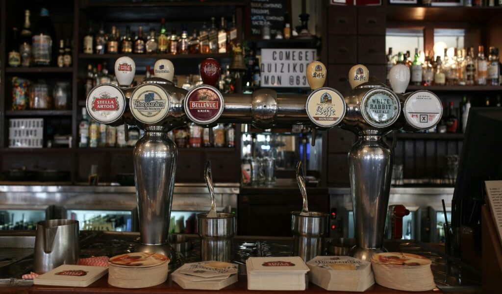 Beer taps labeled Stella Artois, Hoegaarden, Bellevue Kriek, Leffe, and White Rabbit Pale Ale in a cozy pub setting.