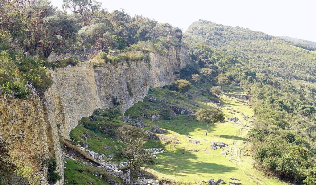 Massive ancient stone walls of Kuelap fortress surrounded by forested hills in Peru.
