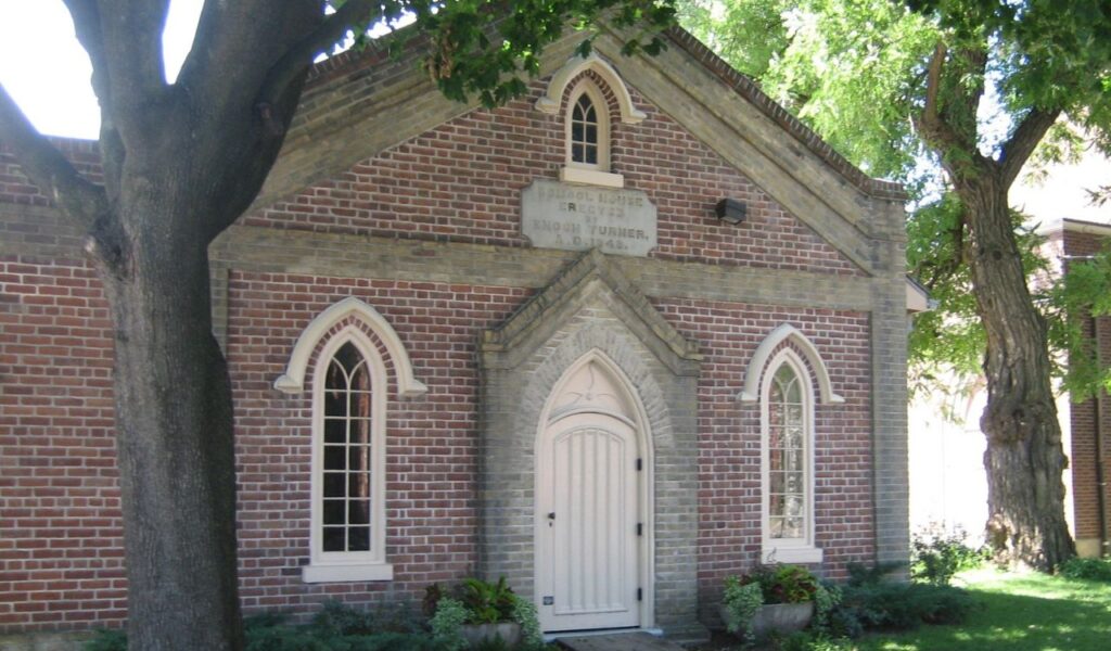 **Alt text (115 characters):**
Charming brick schoolhouse in Ontario, Canada, with arched windows and a white door, now a cozy vacation rental stay.