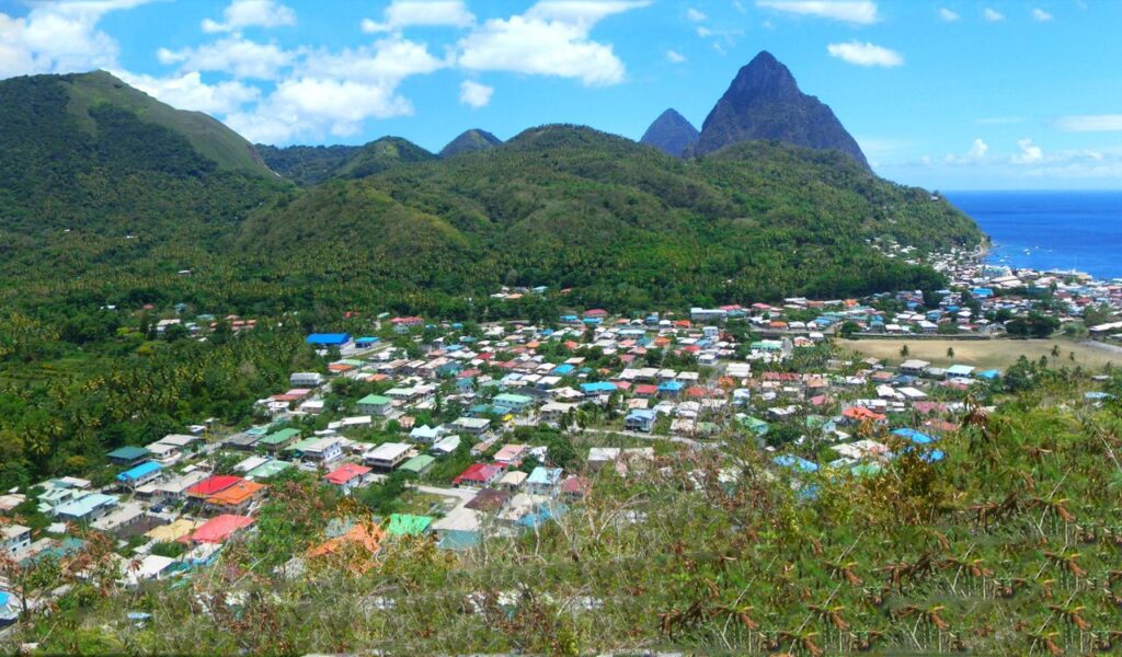 Colorful rooftops spread across the lush hills of Saint Lucia with the iconic Piton mountains in view.