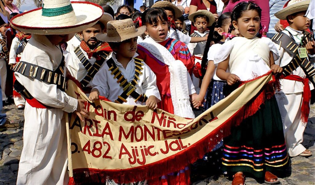 Children in traditional Mexican dress hold a banner during a cultural parade in Ajijic, Jalisco.