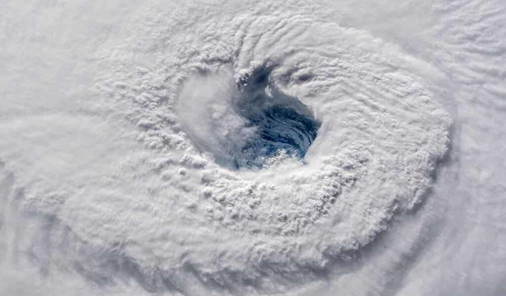 Satellite view of a hurricane’s eye surrounded by swirling clouds, emphasizing the need to monitor storm activity closely.