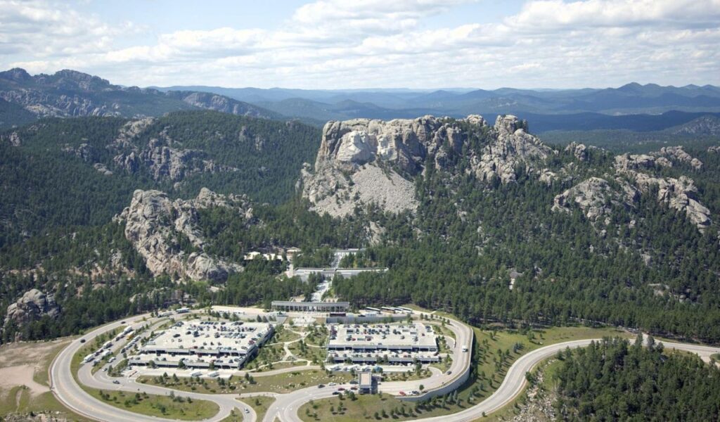 Aerial view of Mount Rushmore surrounded by forested hills and visitor center in South Dakota.
