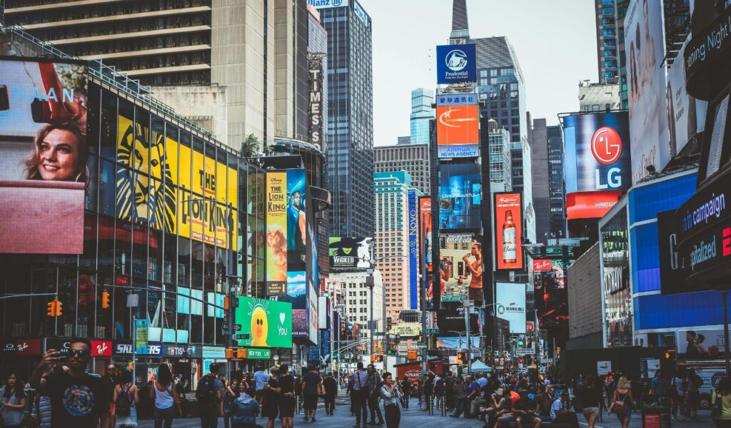 Bustling Times Square in New York City with crowds of people, bright billboards, skyscrapers, and colorful advertisements filling the streets.