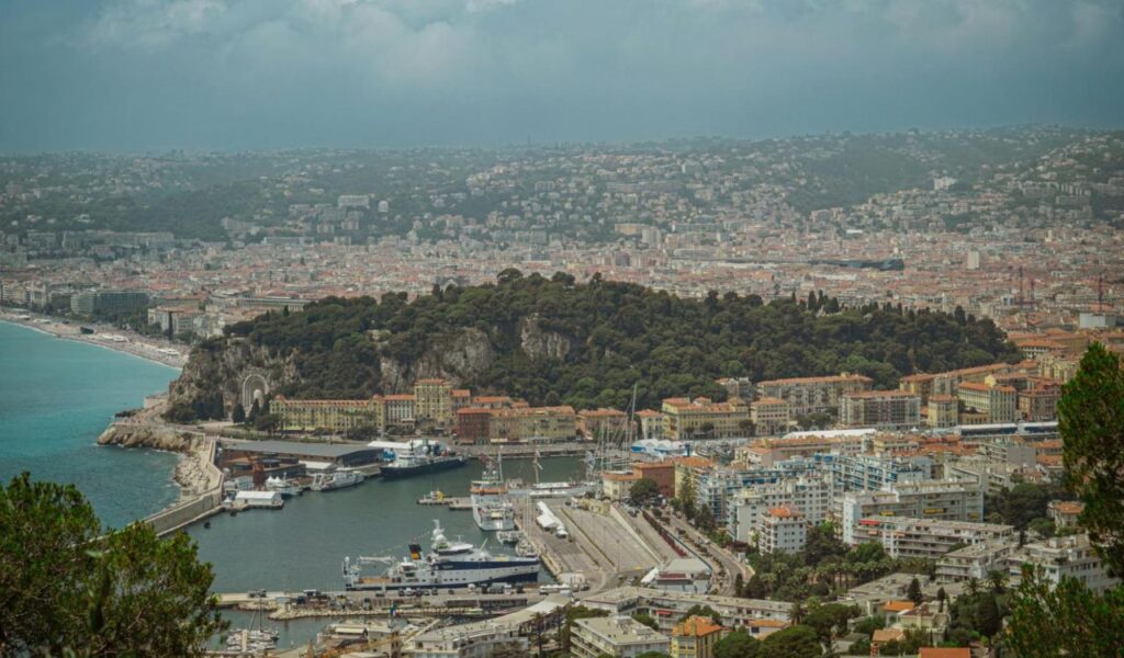 Aerial view of Nice, France showing the harbor, coastline, and densely packed hillside buildings.