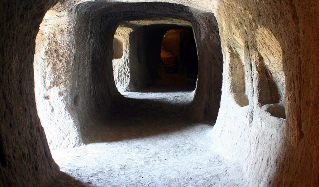 Sunlit stone tunnels inside Orvieto Underground in Italy, with carved walls and intersecting passageways dating back centuries.