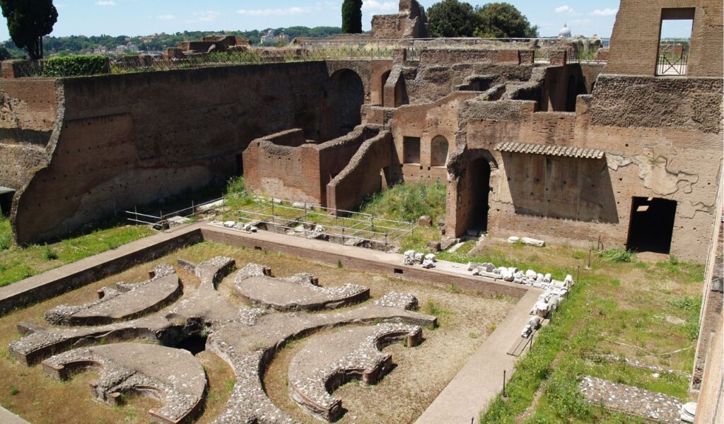 Ruins of ancient Roman structures on Palatine Hill in Rome, with brick walls, arches, and a central sunken design.