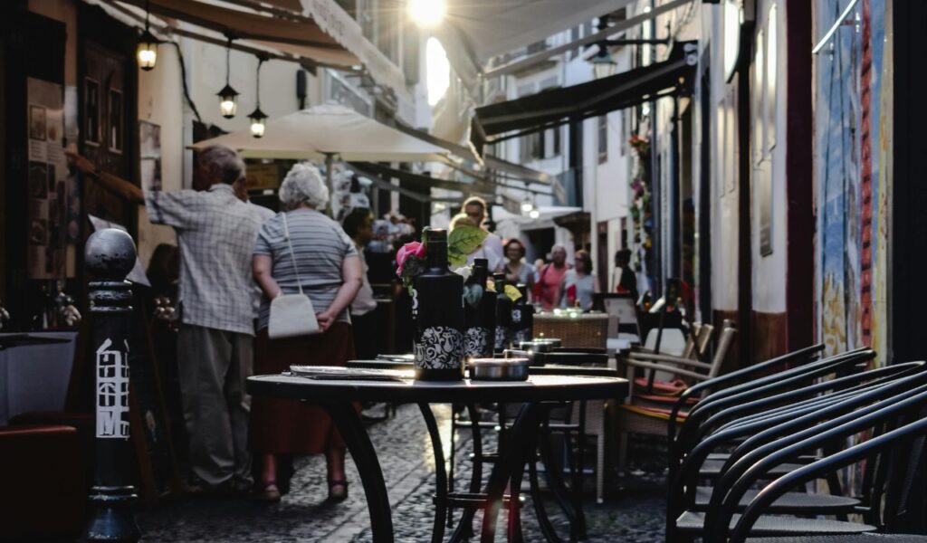 Cozy outdoor café in a narrow Portuguese alleyway with wine bottles on the table—perfect setting for a romantic dinner.