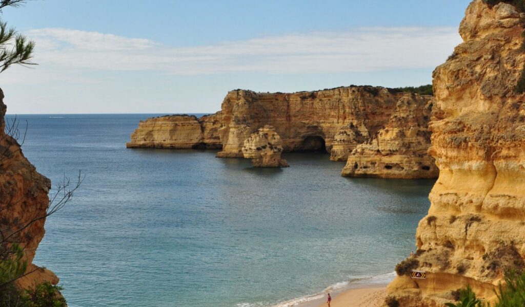Beautiful coastal view of golden cliffs and clear blue waters along the Algarve region in Portugal, with a peaceful beach.