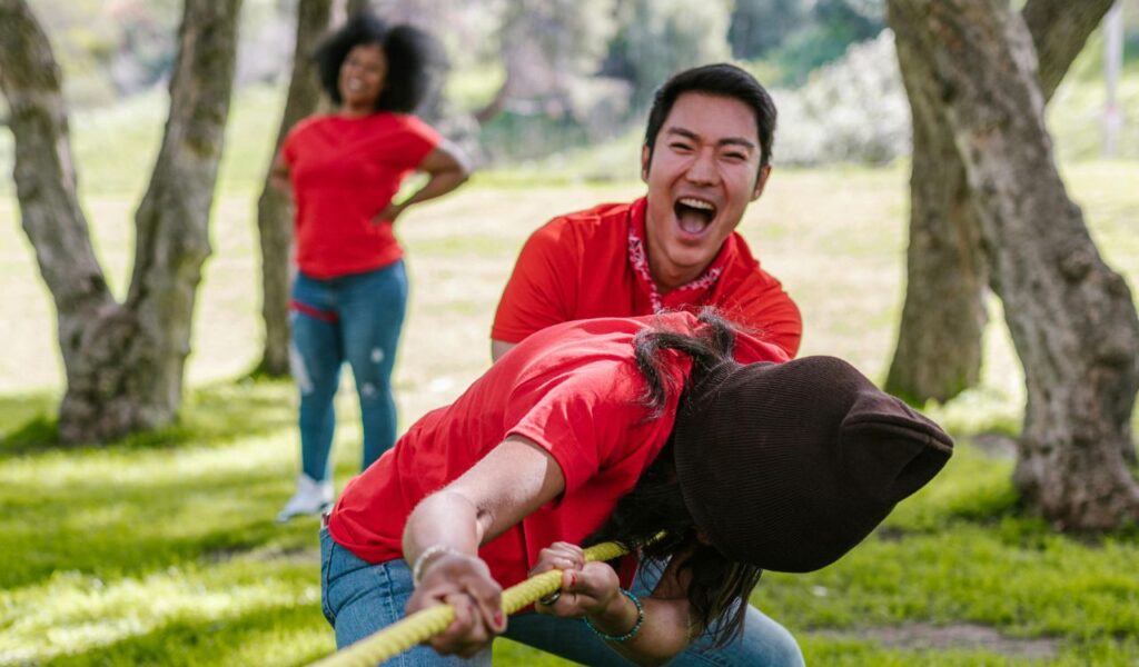 A group of people participating in a fun outdoor tug-of-war game, laughing and enjoying the competition.