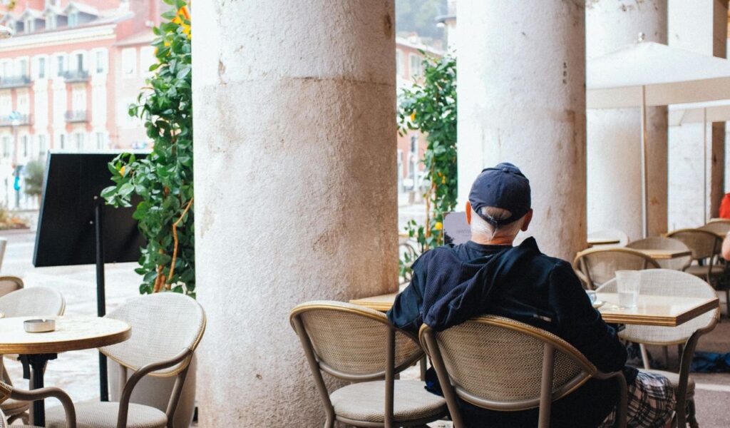 Senior man relaxing and enjoying time at a café, reflecting and unwinding in a peaceful travel setting.