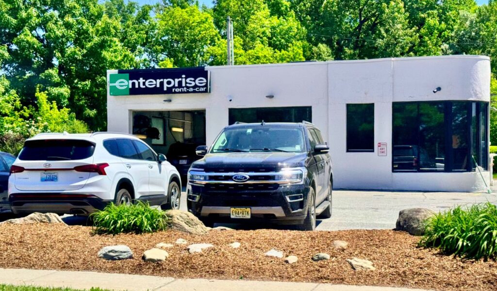 Enterprise Rent-A-Car office with parked vehicles, representing rental car bookings and possible add-on or fuel charges.