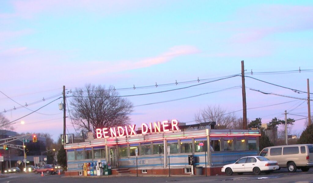 Classic roadside diner with neon "Bendix Diner" sign at dusk, capturing vintage Americana and retro road trip culture.