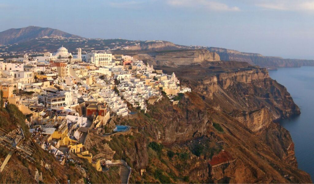 Panoramic view of Fira, Santorini with white buildings perched on cliffs overlooking the Aegean Sea.