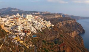 Panoramic view of Fira, Santorini with white buildings perched on cliffs overlooking the Aegean Sea.